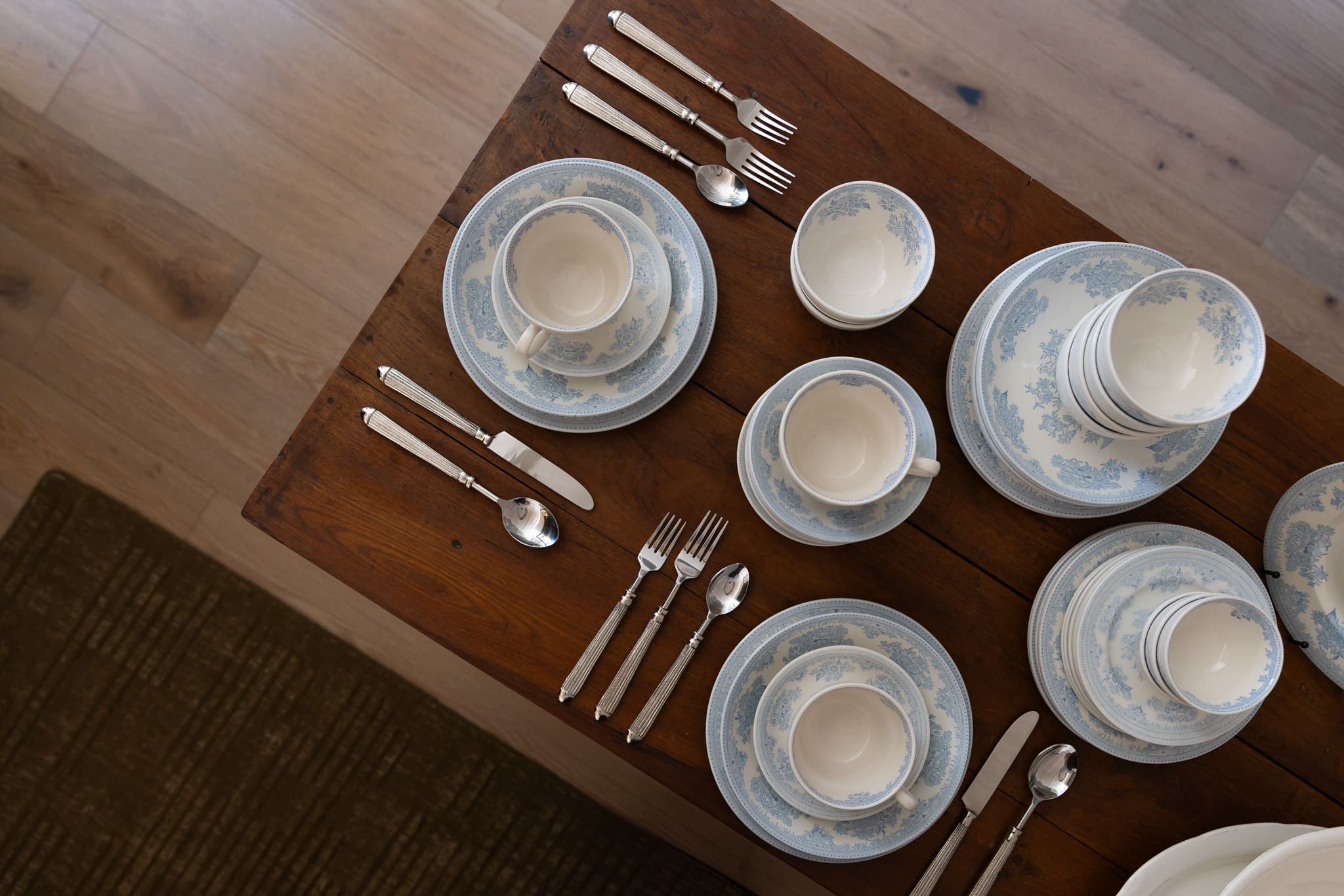 Wood dining table set with blue and white plates, cups and silverware